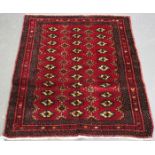 An Afghan rug, mid/late 20th century, the dark claret field with three columns of multiple guls,