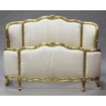 A 20th century Louis XV style gilded and upholstered double bed frame, carved with leaf and flower