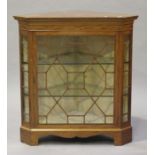 An Edwardian satinwood corner display cabinet with crossbanded borders, the moulded pediment above