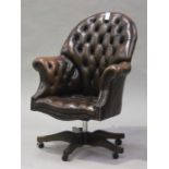 A modern brown buttoned leather revolving office chair with brass studwork decoration, height 110cm,