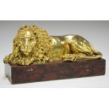 A late 19th/early 20th century gilded cast bronze model of a recumbent lion, on a rose marble