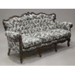 A late 20th century Italianate stained showframe settee with carved decoration, upholstered in