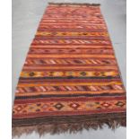 A kelhim rug, early 20th century, with overall polychrome geometric bands, 405cm x 137cm.Buyer’s