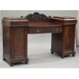 An early 19th century figured mahogany twin pedestal sideboard, the carved leaf scroll back above