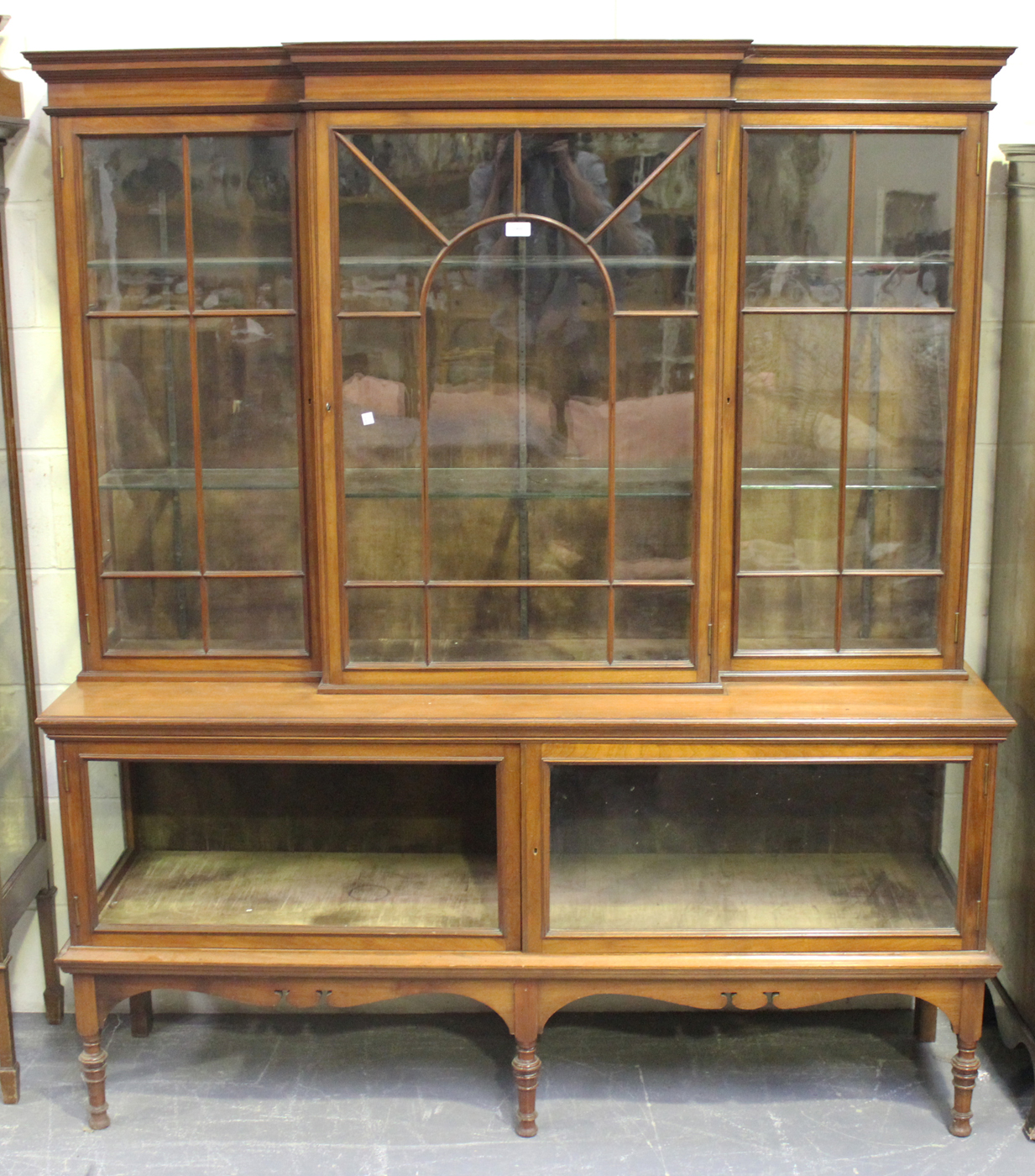 A late Victorian walnut breakfront display cabinet, the moulded pediment above three astragal glazed