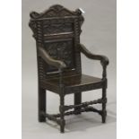 A late Victorian oak Wainscot style armchair, carved with leaves, flowers and mythical beasts, the