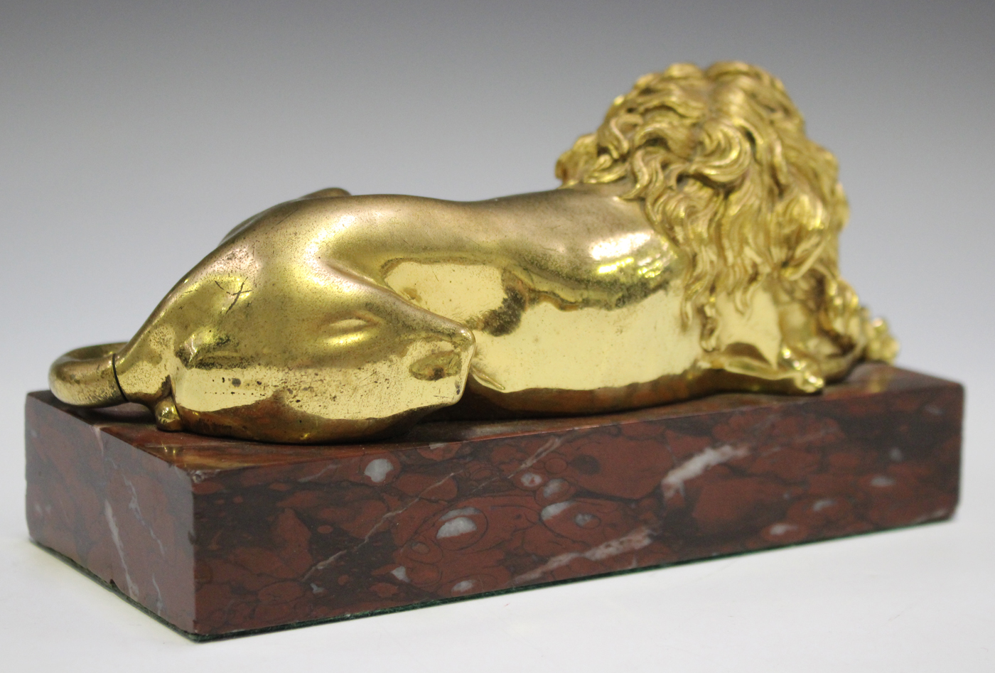 A late 19th/early 20th century gilded cast bronze model of a recumbent lion, on a rose marble - Image 2 of 4