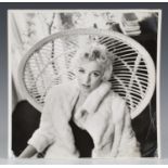 BEATON, Cecil. A black and white photograph of Marilyn Monroe seated in a wicker chair, 28cm x 28cm,