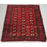An Afghan rug, mid/late 20th century, the dark claret field with three columns of multiple guls,