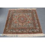 A Turkish silk rug, late 20th century, the ivory field with a shaped salmon pink medallion, within a