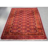A machine made Turkestan style rug, mid-20th century, the deep red field with overall columns of