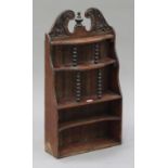 A late 19th century walnut wall shelf with a carved foliate crest and turned spindle supports,