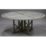 A large late 20th century teak slatted garden table, the circular top above 'X' framed supports,