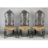 A set of three mid-18th century Continental Rococo carved walnut hall chairs, each back profusely