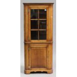 A late 20th century reproduction oak corner cabinet, the glazed door above a panelled door, on