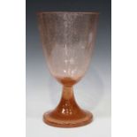 A large pink tinted glass goblet shaped vase, on a spread circular foot, with bubble inclusions,