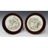 A pair of French bisque porcelain circular wall plaques, circa 1900, each moulded in high relief
