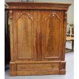 A Victorian figured mahogany wardrobe, the moulded pediment above a pair of arched panel doors and a