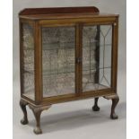 An early 20th century mahogany display cabinet with leaded glazed doors, on cabriole legs and claw