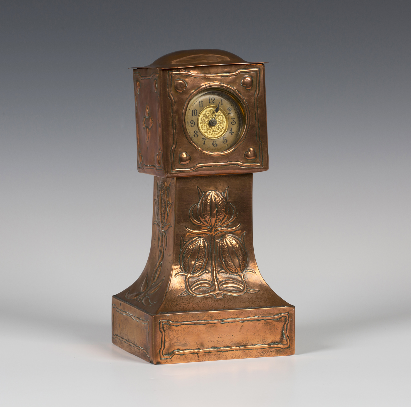 A late 19th/early 20th century Arts and Crafts copper mantel timepiece of longcase clock form,
