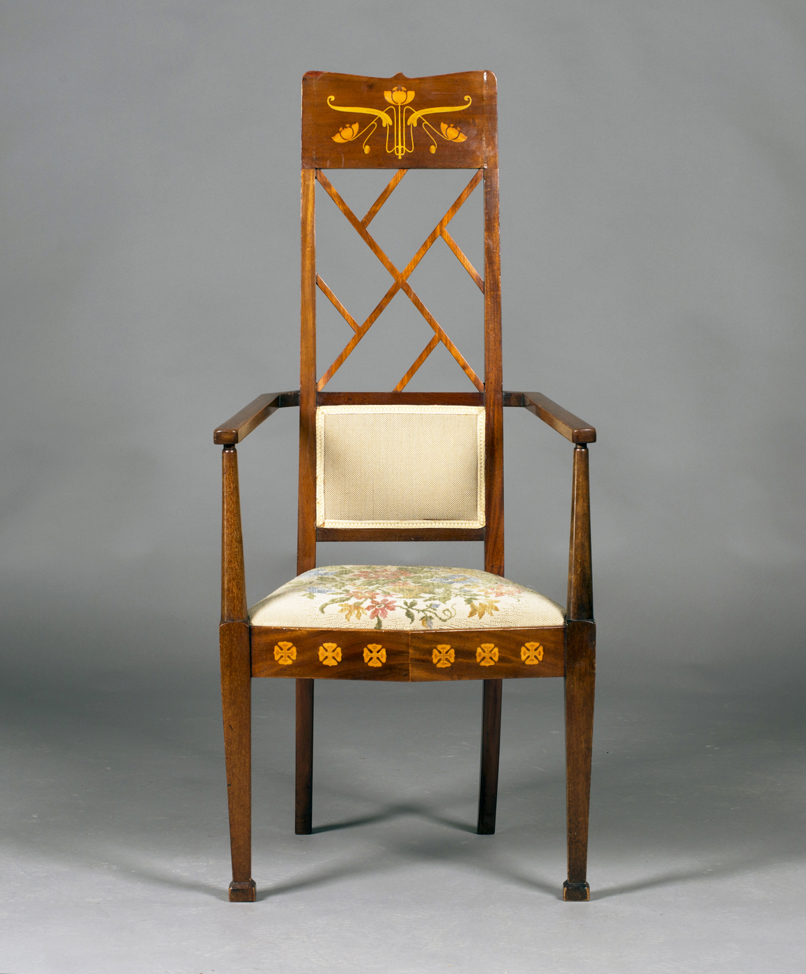 An Edwardian Arts and Crafts mahogany and foliate inlaid elbow chair, possibly by J.S. Henry, the