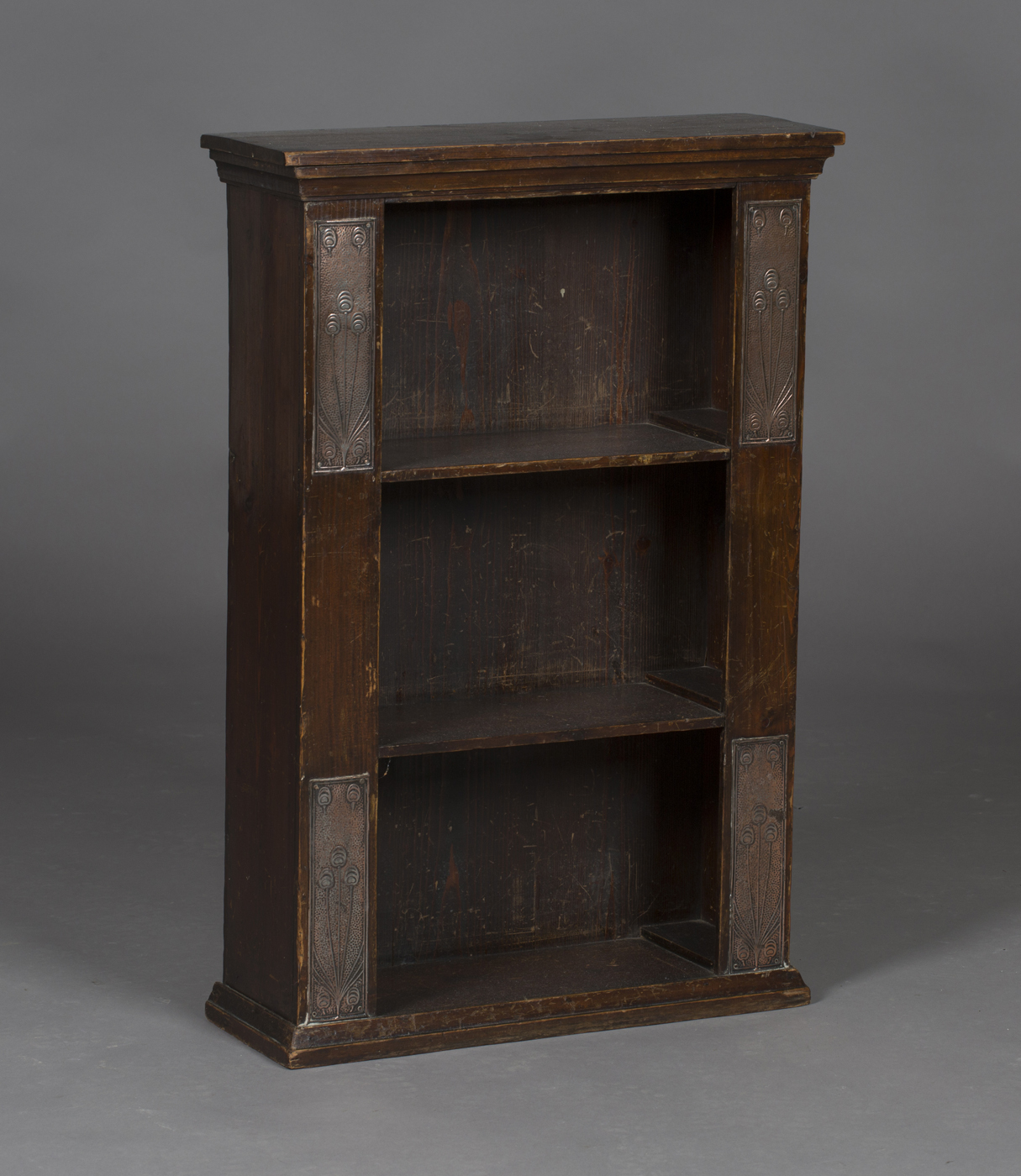 An early 20th century Arts and Crafts style stained pine open bookshelf, the sides with four applied