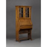 An Edwardian Arts and Crafts oak bureau bookcase, the canopy pediment above a pair of stained and