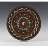 A Ray Finch, Winchcombe studio pottery charger, the iron rich glaze with white trailed decoration,