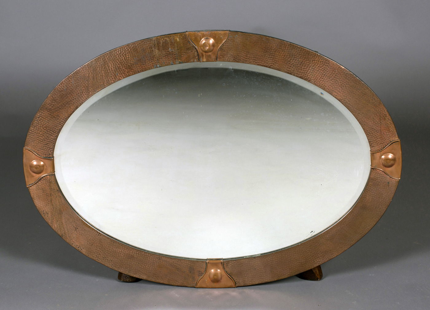 An early 20th century Arts and Crafts style copper framed oval wall mirror, 89cm x 63cm.Buyer’s