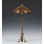 An Arts and Crafts brass table lamp, in the manner of W.A.S. Benson, the domed copper shade on three
