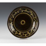 A Clive Bowen studio pottery shallow bowl, the dark brown glazed body with yellow slip decoration,