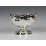 An Edwardian Arts and Crafts style silver rose bowl, the wavy rim above a hammered body, decorated