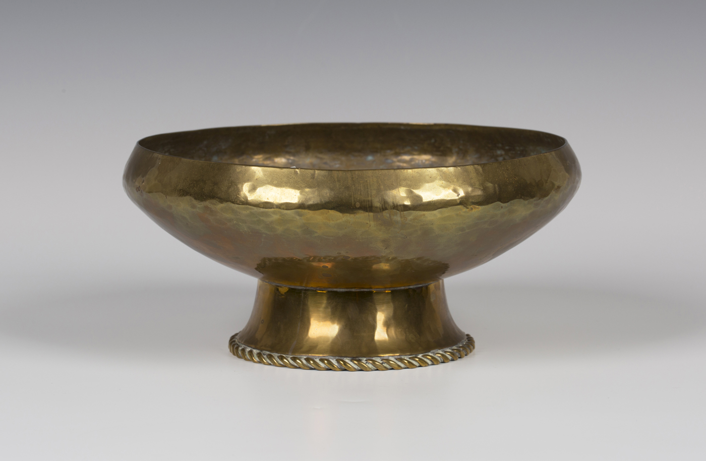 An Arts and Crafts brass circular bowl by Hugh Wallis with an overall hammered body, the spreading