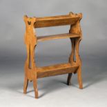 An Edwardian Arts and Crafts Liberty style oak book trough, the three tiers supported by pierced