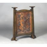 An early 20th century Arts and Crafts walnut framed firescreen, the panel carved in relief with a