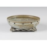 A Chinese studio pottery archaic type bowl, raised on three shaped feet, covered in a green and grey