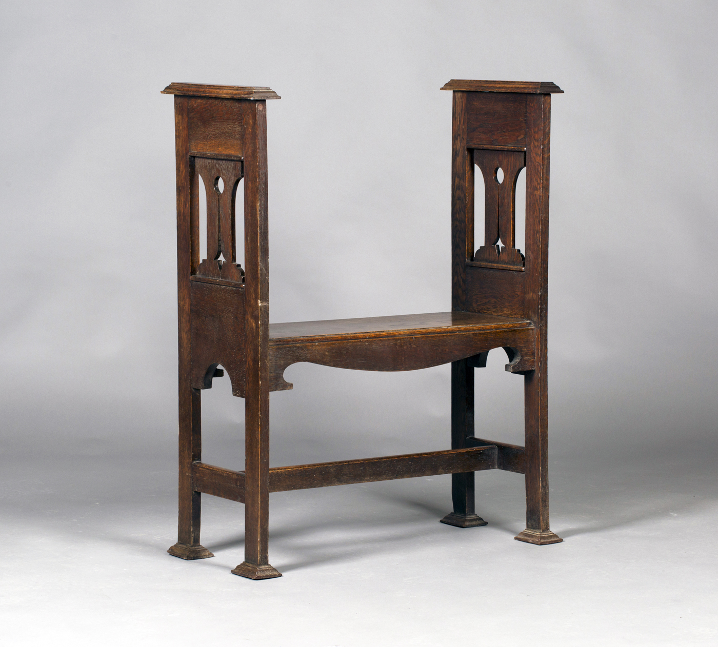 An Edwardian Arts and Crafts oak window seat, the solid seat flanked by pierced sides, the block