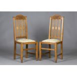 A pair of Edwardian Arts and Crafts oak side chairs, probably by Wylie & Lochhead, the arched top