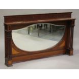 An Edwardian mahogany overmantel mirror, the wide shield shaped bevelled glass within a surround