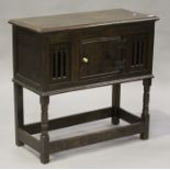 A 17th century style oak food cupboard, the moulded top panel above a cupboard door and two