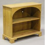 A 20th century pine two-tier open bookcase with an arched frieze, raised on shaped bracket feet,