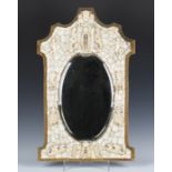 A 19th century French Dieppe ivory mounted wall mirror of shaped outline, the oval bevelled glass