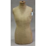 An early 20th century dressmaker's dummy torso with fabric covered body, height 83cm.Buyer’s Premium