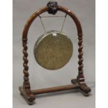 A late Victorian walnut dinner gong stand, carved with a lion's mask, raised on barley twist