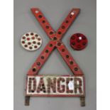 A red and white coated metal 'X' shaped 'Danger' road sign, inset with overall reflectors,