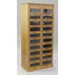 An Art Deco oak haberdashery cabinet by Dudley & Co Ltd, London, fitted with twenty glazed sliding