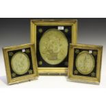 A group of three Regency oval silkwork floral panels, each mounted within a verre églomisé border