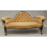 A mid-Victorian walnut showframe salon settee, upholstered in peach velour, raised on carved foliate