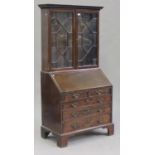 A George III mahogany bureau bookcase, the dentil moulded pediment above a pair of astragal glazed