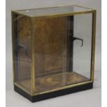 An early 20th century brass framed shop display cabinet, fitted with sliding doors above a parquetry